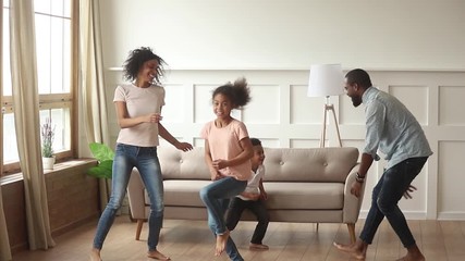 Wall Mural - African family with kids active spending time dancing at home