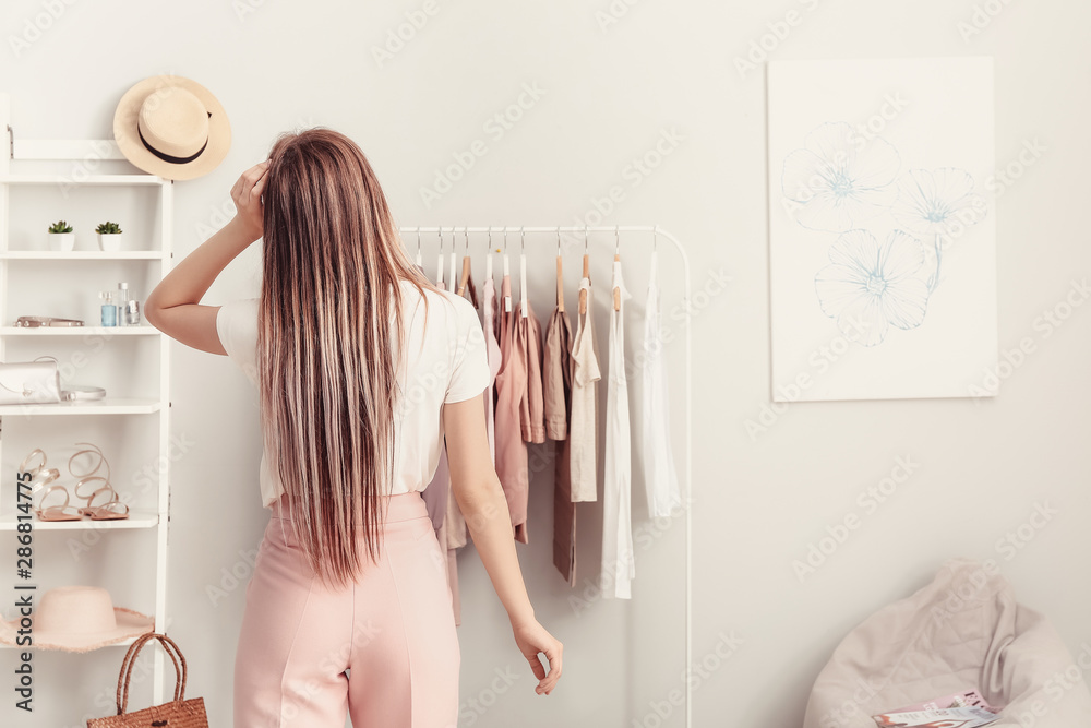 Young woman choosing clothes in her dressing room, back view