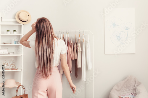 Cuadros en Lienzo Young woman choosing clothes in her dressing room, back view