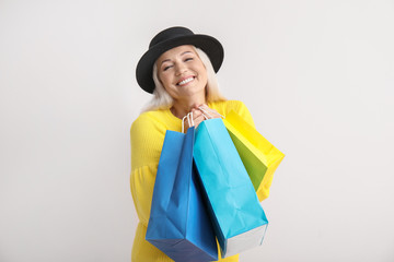 Wall Mural - happy mature woman with shopping bags on light background