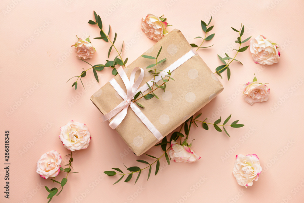 Gift box and beautiful flowers on color background
