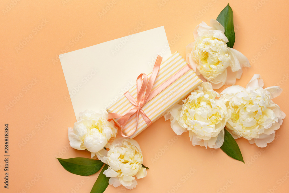 Gift box, blank card and beautiful flowers on color background