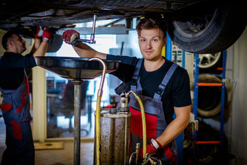 Car mechanic changes oil in a workshop