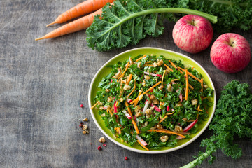 Wall Mural - Healthy cabbage kale salad with carrots, apple and walnut on wooden background. delicious homemade diet food