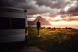 Ein mann steht neben einem Campervan an einer Bucht im Hintergrund ein Berg bei Sonnenuntergang
