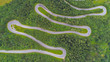 AERIAL: Cars driving along scenic mountain highway with sharp hairpin turns