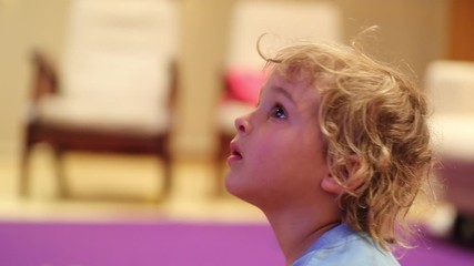 Wall Mural - Candid cute little boy toddler watching TV screen hypnotized