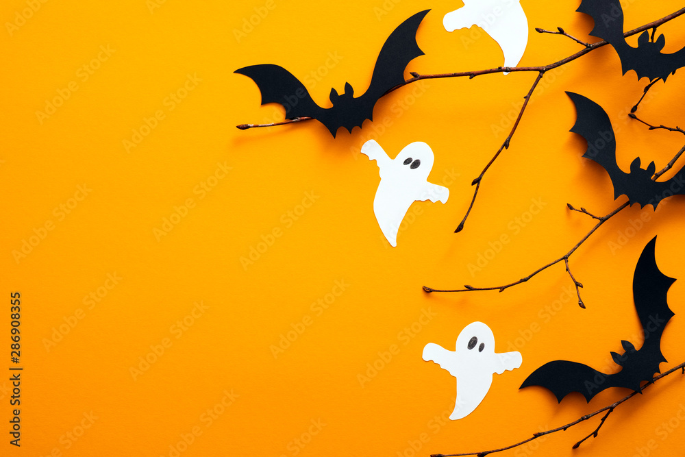 Happy halloween holiday concept. Halloween decorations, bats, ghosts on orange background. Halloween party greeting card mockup with copy space. Flat lay, top view, overhead. - obrazy, fototapety, plakaty 
