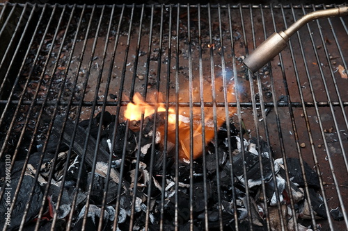Obraz Dibond Zapalniczka z butli z gazem przy grillu z grillem węglowym