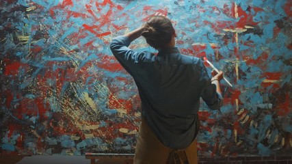 Fototapete - Talented Female Artist Energetically Using Paint Brush She Creates Modern Masterpiece of the Oil Painting. Dark Creative Studio where Large Canvas Stands on Easel Illuminated. Back View Following Shot