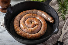Cooked Coiled Sausage On Cast Iron Pan