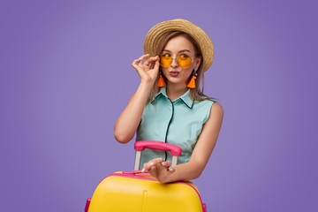 Wall Mural - Trendy young traveler with suitcase pouting lips