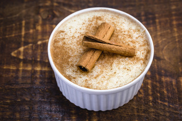 Typical sweet of Brazil in June and July parties. Sweet rice porridge with cinnamon in a bowl on a background.