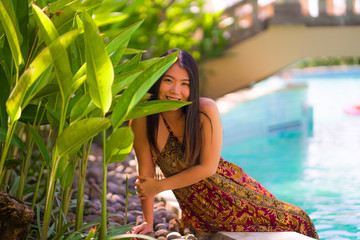 Wall Mural - lifestyle portrait of young beautiful and happy Asian Chinese tourist woman smiling cheerful and natural enjoying Summer holiday getaway at luxury tropical resort