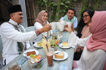 Wall Mural - group of friends having tea toast at table dining during ramadan celebration