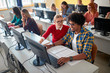 © luckybusiness - Group of students sitting together at table using computer in class .