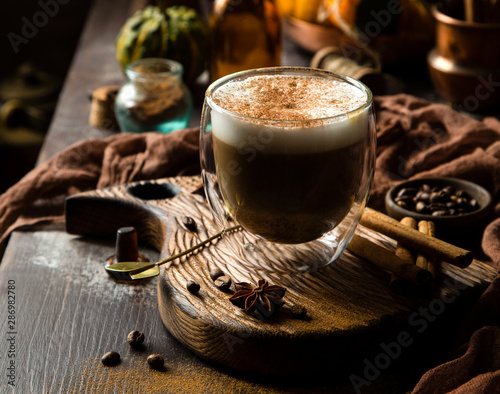 foamy pumpkin spice latte in glass jar on wooden board on rustic brown table Poster Mural XXL