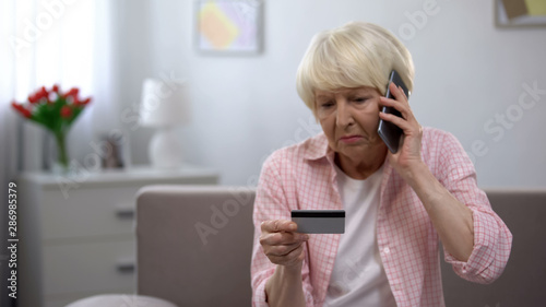 Cuadros en Lienzo Sad old woman with credit card calling bank support, reporting about money fraud