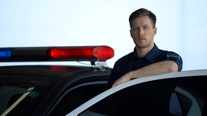 Wall Mural - Handsome police officer standing near car on duty, protection of public safety