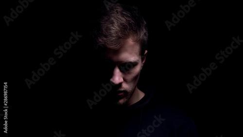 Fotomural Man looking down against black background, feeling guilty for committed crime