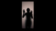 Shadow of scared woman knocking at glass door, escape from captivity, violence