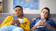 Multiethnic male teenagers scrolling smartphones, leisure time after school