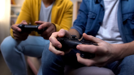 Two multiethnic teenage boys playing computer games at home, hands close-up