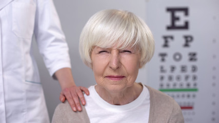 Wall Mural - Ophthalmologist supporting elderly woman with blurred vision, planned check-up