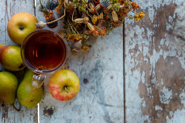 autumn harvest composition with apples pears cup of tea and dry healing herbs on wooden blue table background