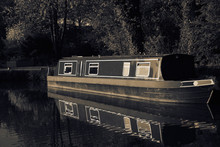 Canal Barge Boat Moored On The Shropshire Union Canal, Reflected In The Water.  Sepia Toned