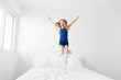 © Lisa Tichané - Young girl jumping with joy on white bed