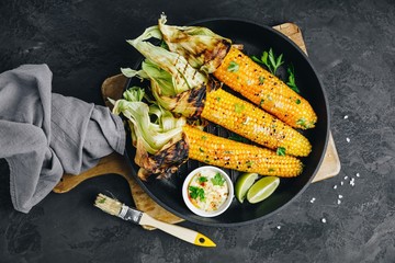 Roasted or grilled sweet corn cobs with garlic butter and lime.