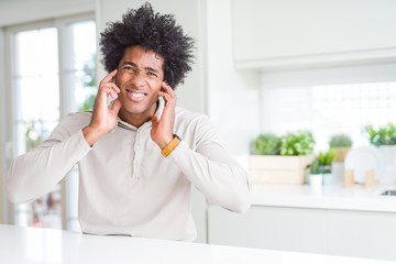 Sticker - African American man at home covering ears with fingers with annoyed expression for the noise of loud music. Deaf concept.