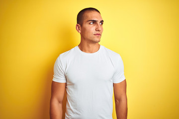 Canvas Print - Young caucasian man wearing casual white t-shirt over yellow isolated background smiling looking to the side and staring away thinking.