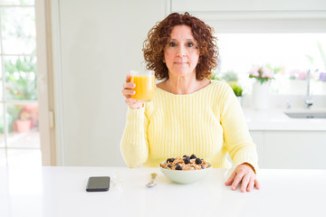 Poster - Senior woman eating healthy breakfast in the morning at home with a confident expression on smart face thinking serious