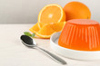 Plate with tasty orange jelly served on white wooden table, space for text
