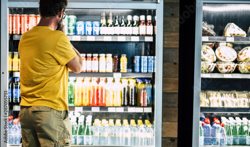 man alone and isolated at the supermarket or minimarket choosing his drink or sn Fototapeta