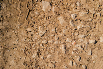 Wall Mural - Dry soil texture and background. Red soil background. Abstract ground. Natural abstraction. Clay. Ocher. Red sands. Tire tracks. Clayey ground. Stony ground