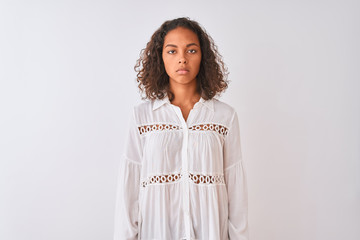 Canvas Print - Young brazilian woman wearing shirt standing over isolated white background with serious expression on face. Simple and natural looking at the camera.