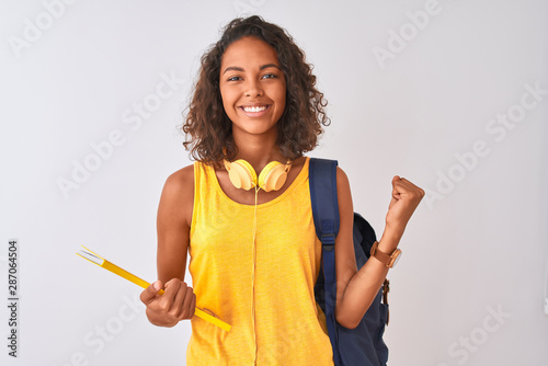 Fotomural Brazilian student woman wearing backpack holding notebook over isolated white ba