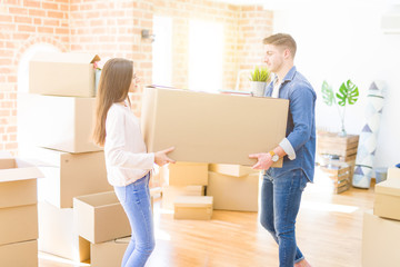 Poster - Beautiful young couple smiling in love holding a big cardboard box, happy for moving to a new home