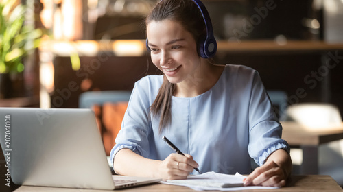 Fotomural Smiling girl wear wireless headphone study online with skype teacher