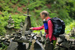 © Андрей Репетий - Traveling girl with a backpack putting stones and small rocks in the forest. The tower of falls.