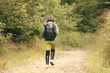 © Андрей Репетий - Traveling slim girl with backpack walking in wilderness through the forest. Back view.