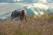 © Андрей Репетий - Happy woman hiker climbing up mpuntain through high and dry grass