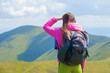 © Андрей Репетий - Young girl hiker with backpack looking into the distance standing on the top of mountain
