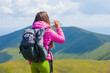© Андрей Репетий - Female tourist with backpack drinking water in the mountains. Woman resting with water bottle during hike.