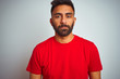 © Krakenimages.com - Young indian man wearing red t-shirt over isolated white background with serious expression on face. Simple and natural looking at the camera.
