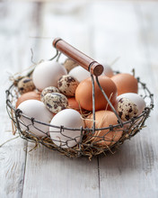 Basket Of Colorful Fresh Eggs On Wooden Table