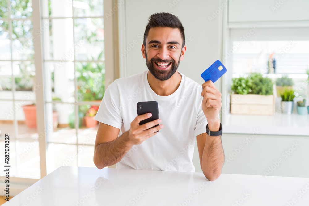 Handsome man using credit card to pay online with smartphone Stock ...